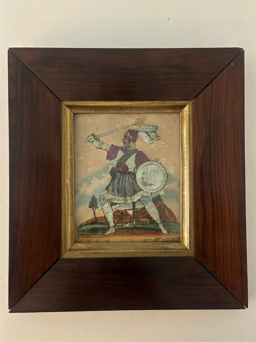 A pair of framed Regency theatrical tinsel pictures depicting armoured figures with weapons set inside dark wood frames with gold slips. View II