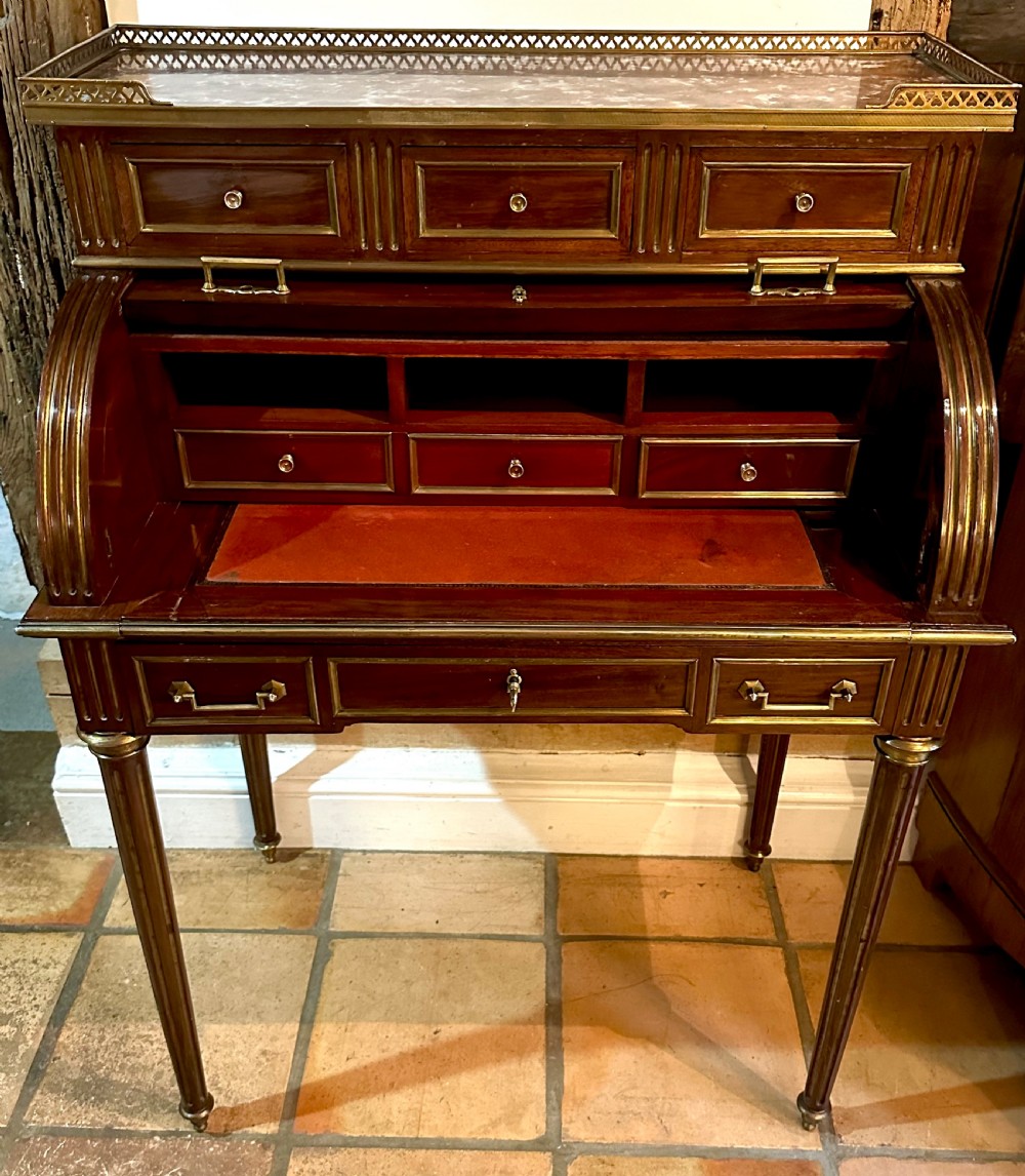 A mahogany French cylinder escritoire featuring a central painted pastoral scene on the roll-top, upper drawer tier, brass mounts, and slender fluted legs. View IX