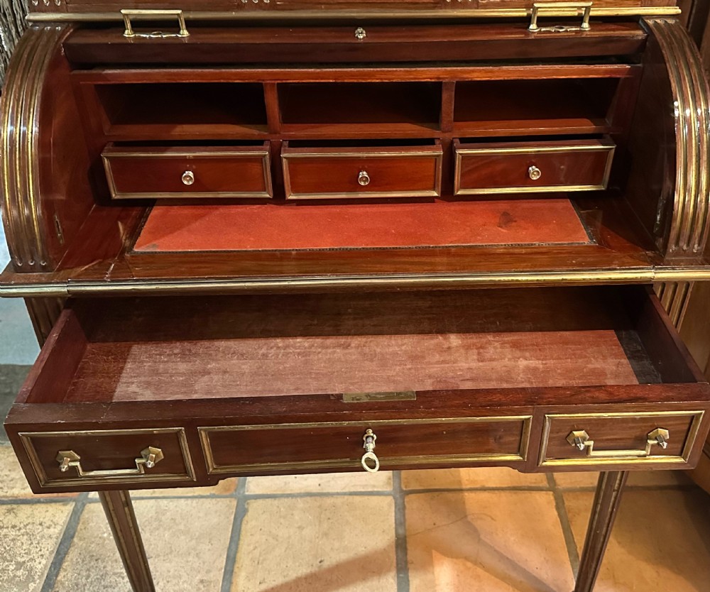 A mahogany French cylinder escritoire featuring a central painted pastoral scene on the roll-top, upper drawer tier, brass mounts, and slender fluted legs. View XI