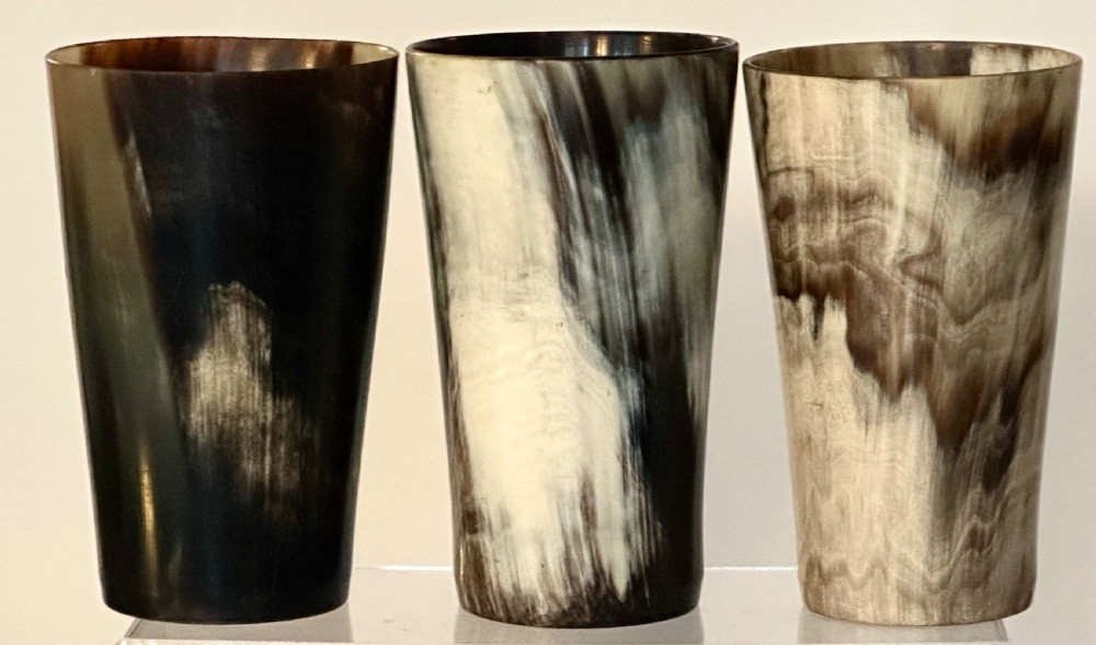 A set of three cylindrical antique drinking beakers made from polished natural horn with variegated cream, amber, and dark brown graining. View II