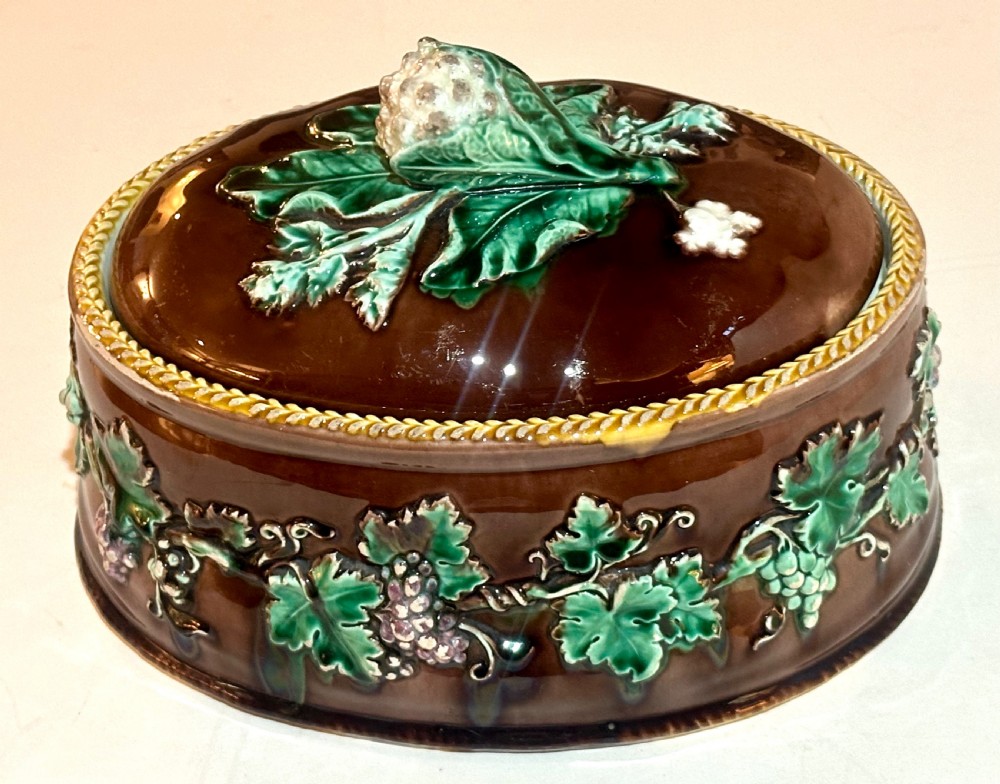 An oval dark brown glazed earthenware tureen featuring relief-moulded green vine leaves and a cauliflower finial on the lid. View II