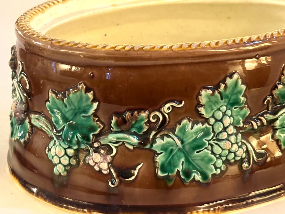 An oval dark brown glazed earthenware tureen featuring relief-moulded green vine leaves and a cauliflower finial on the lid. View VIII