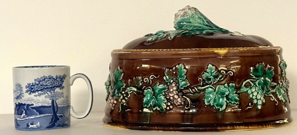 An oval dark brown glazed earthenware tureen featuring relief-moulded green vine leaves and a cauliflower finial on the lid. View IX