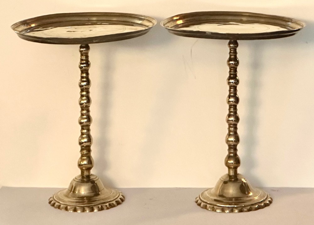 A pair of polished brass pedestal platters featuring turned baluster stems and circular trays on stepped round bases.