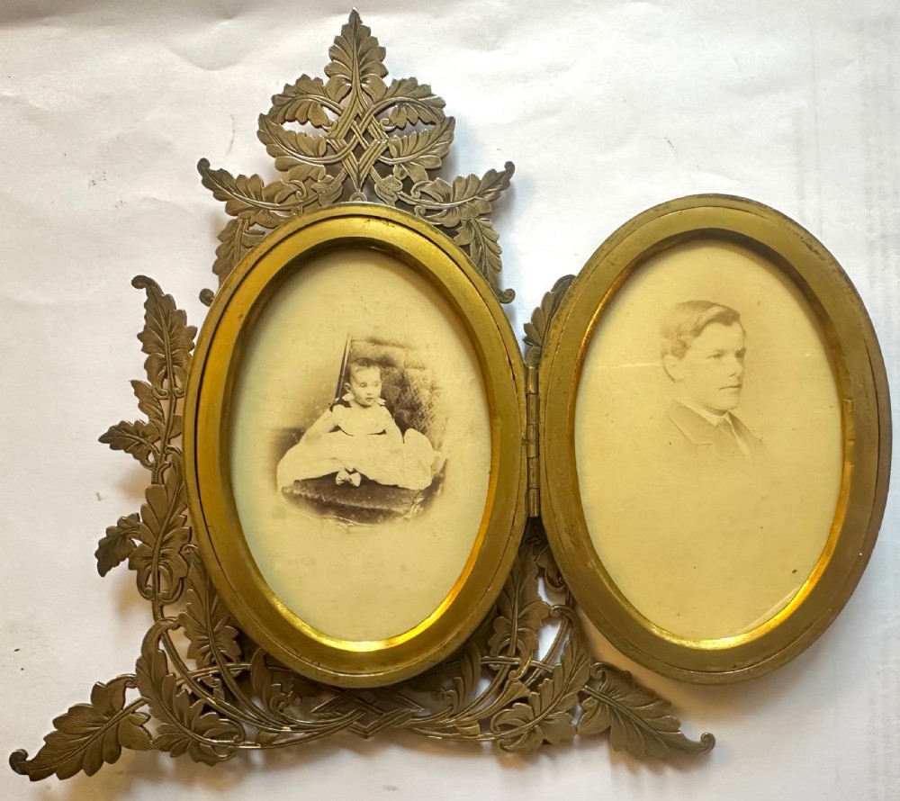 An ornate Victorian brass double picture frame featuring two oval apertures framed by detailed foliate metalwork and an easel stand. View II