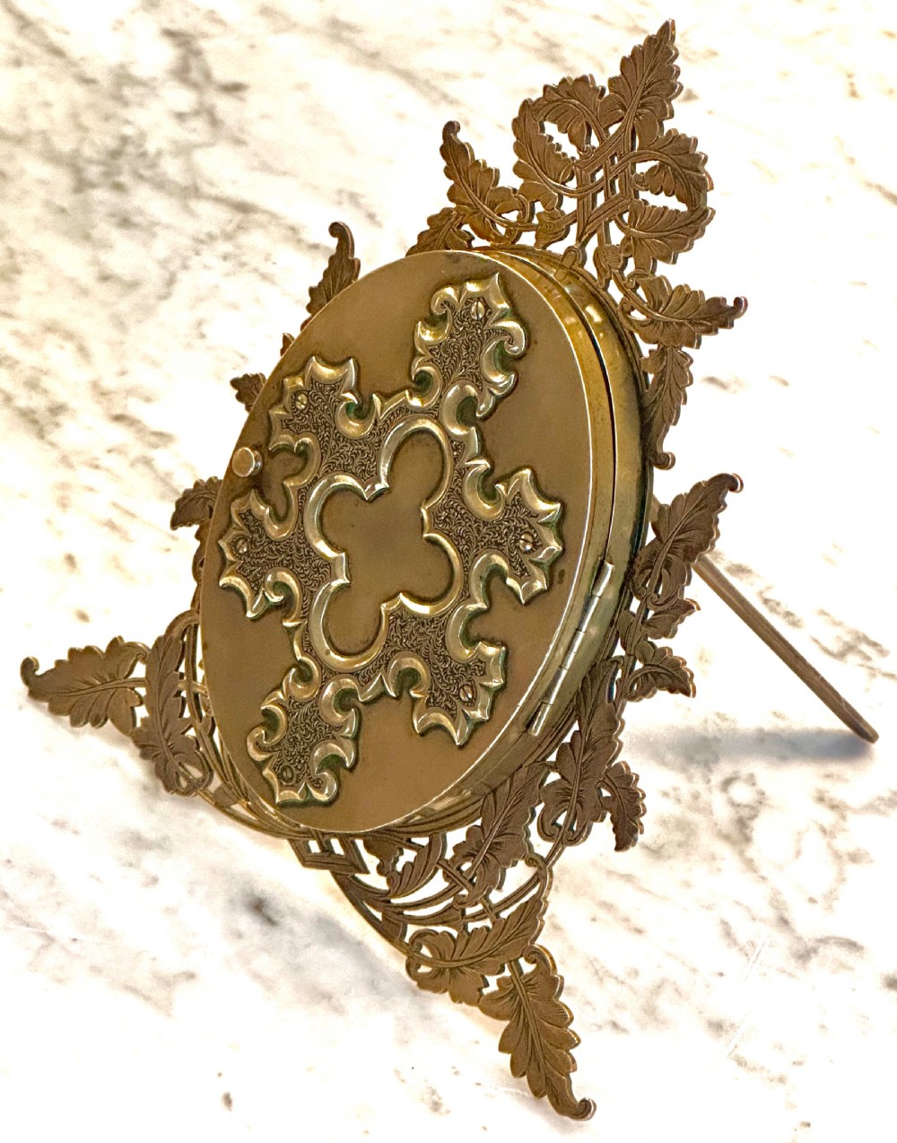 An ornate Victorian brass double picture frame featuring two oval apertures framed by detailed foliate metalwork and an easel stand. View IV