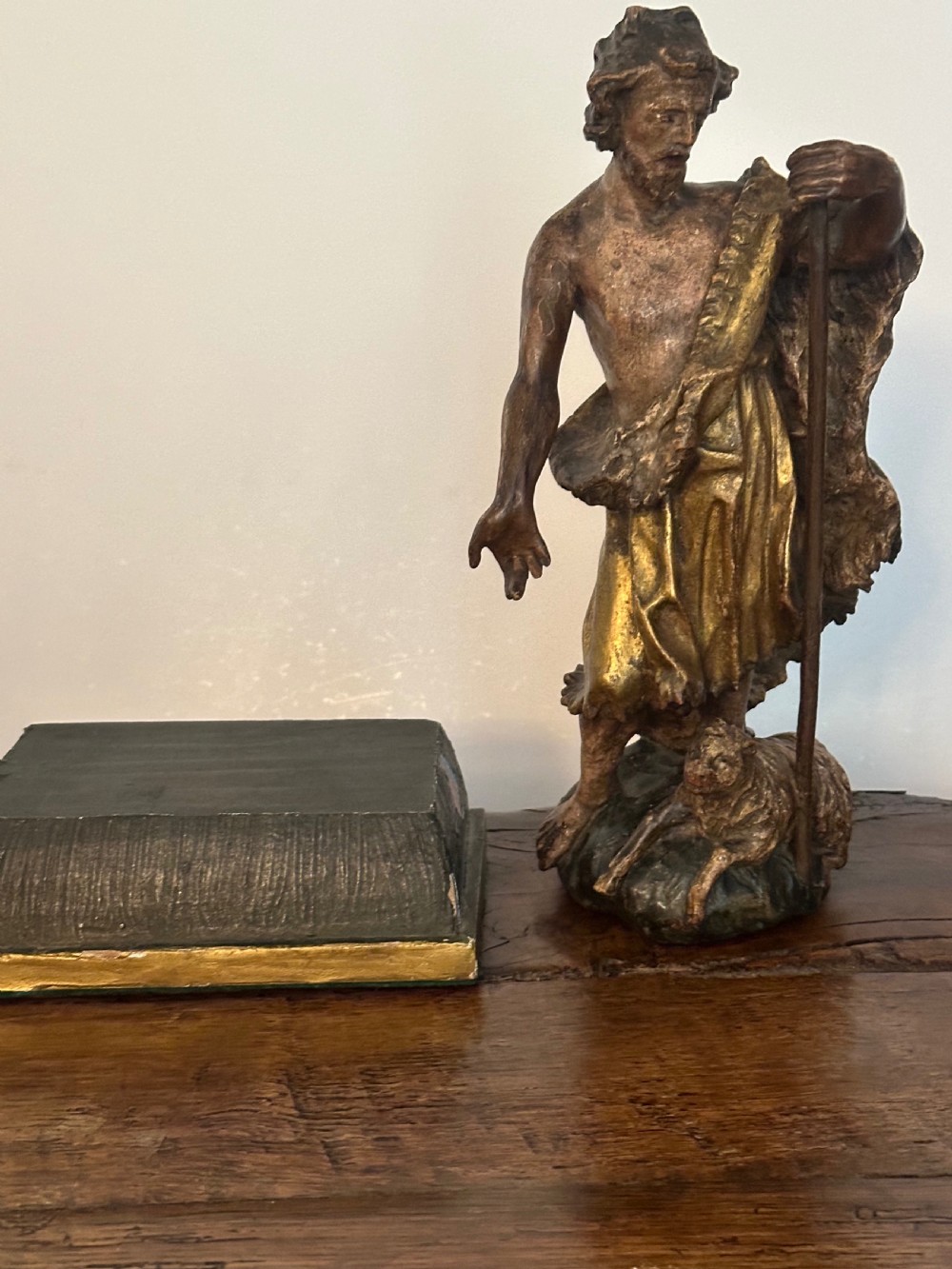 A 17th-century parcel-gilded bronze figure depicting Saint John the Baptist with a staff and lamb, standing on a rectangular wood plinth base. View IX