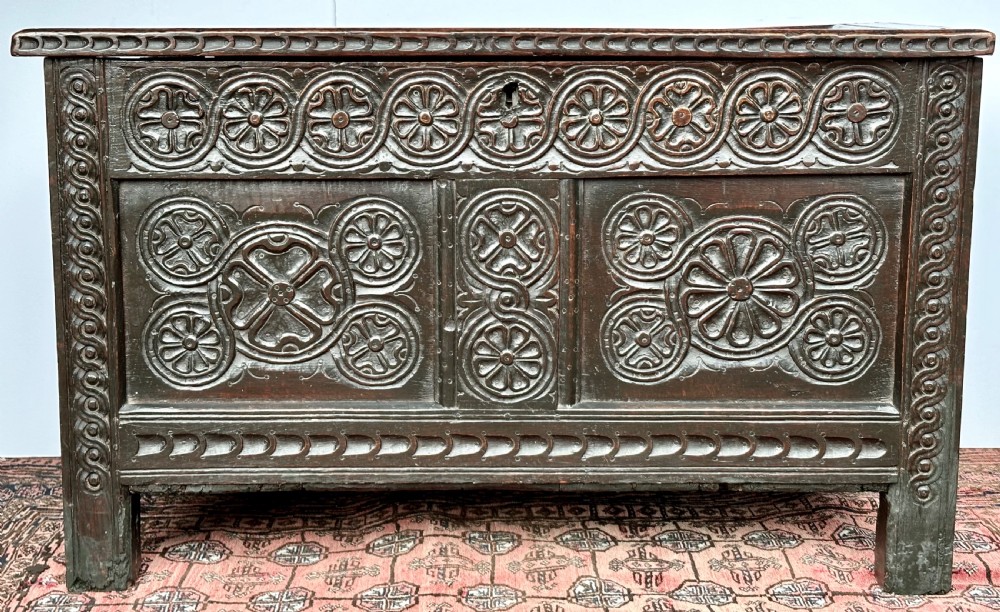A dark oak coffer featuring three panelled front sections with carved rosette motifs and a carved top frieze. View IV