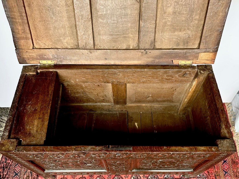 A dark oak coffer featuring three panelled front sections with carved rosette motifs and a carved top frieze. View VI