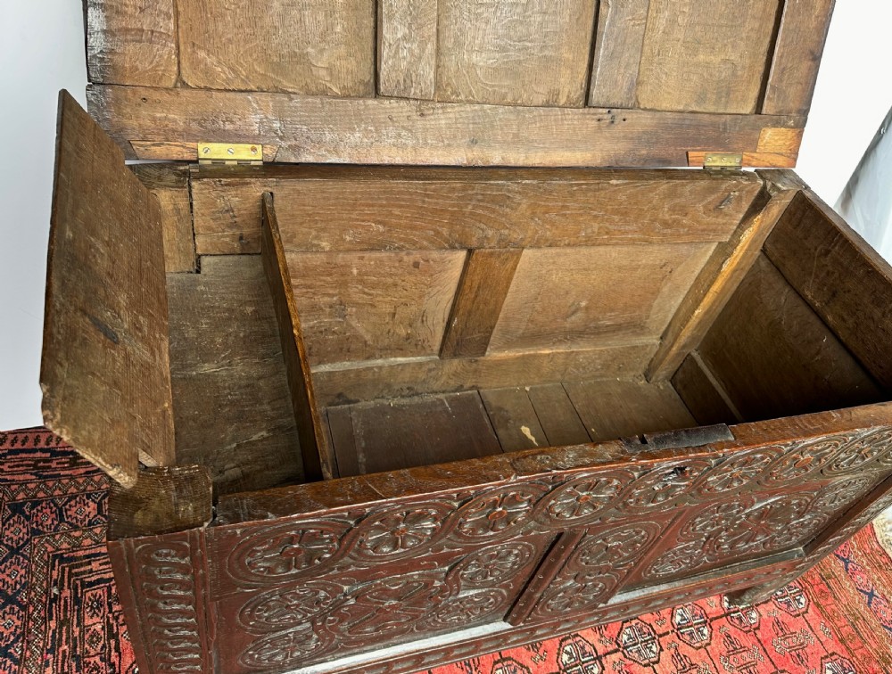 A dark oak coffer featuring three panelled front sections with carved rosette motifs and a carved top frieze. View VII