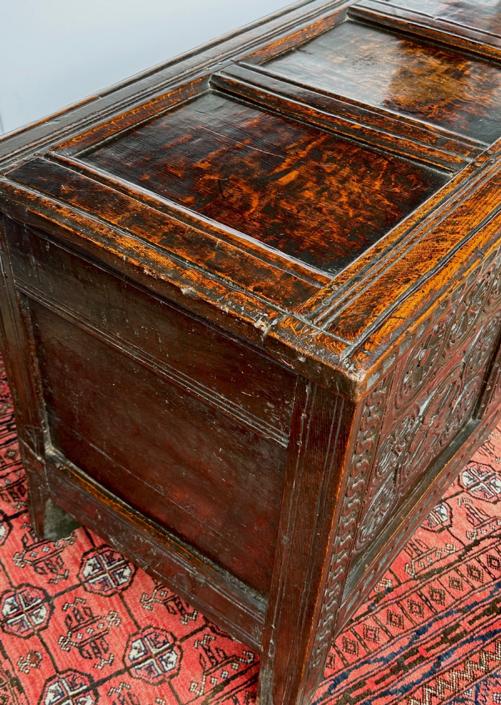 A dark oak coffer featuring three panelled front sections with carved rosette motifs and a carved top frieze. View VIII