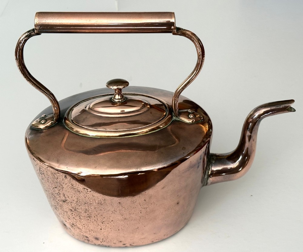 An antique copper tea kettle featuring a gooseneck spout, stationary overhead handle, and fitted lid with a central finial. View III