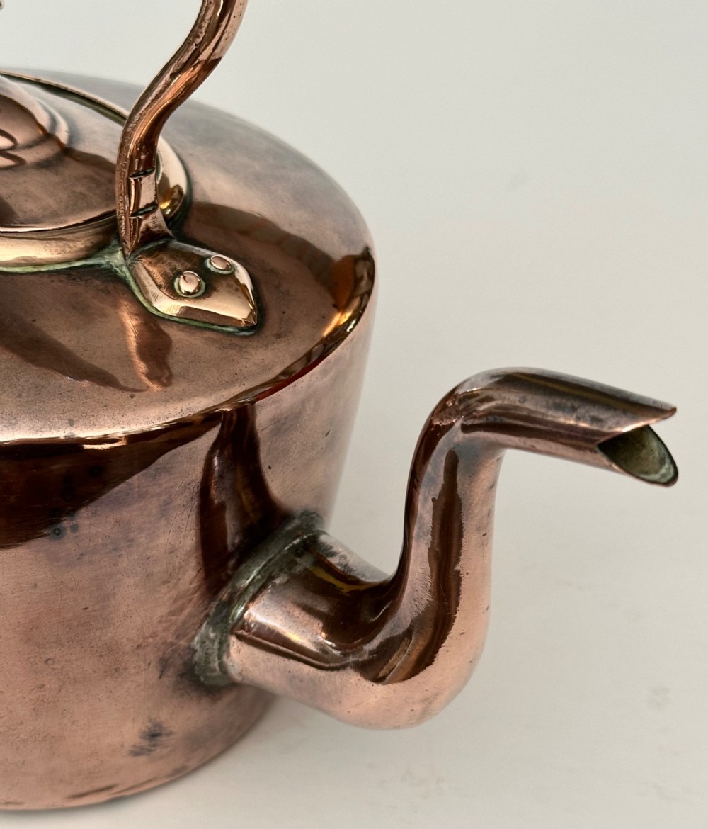 An antique copper tea kettle featuring a gooseneck spout, stationary overhead handle, and fitted lid with a central finial. View IV