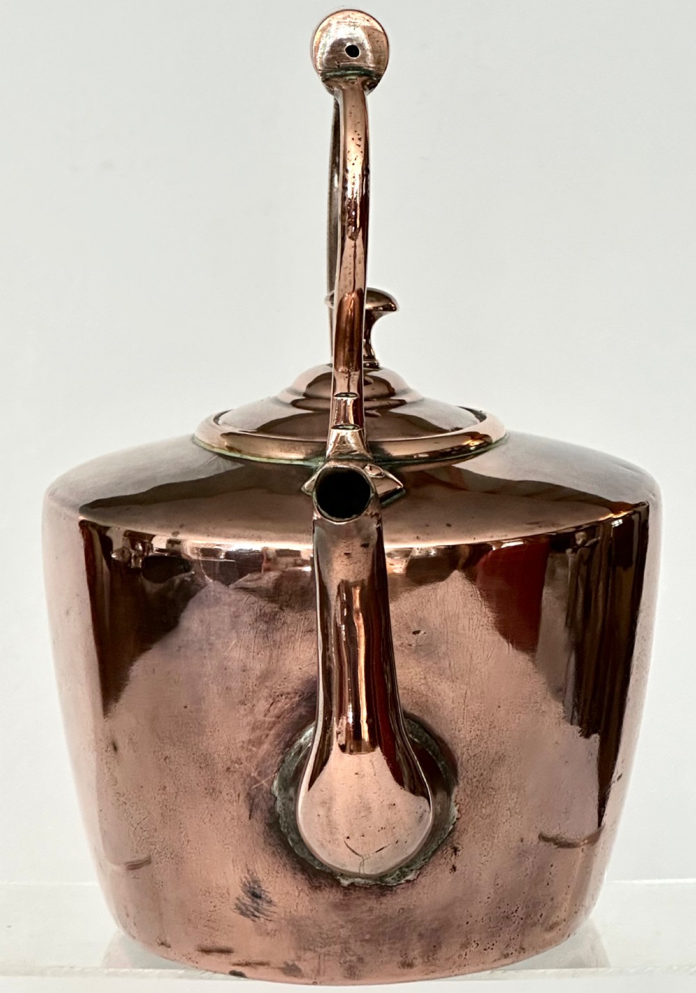 An antique copper tea kettle featuring a gooseneck spout, stationary overhead handle, and fitted lid with a central finial. View V