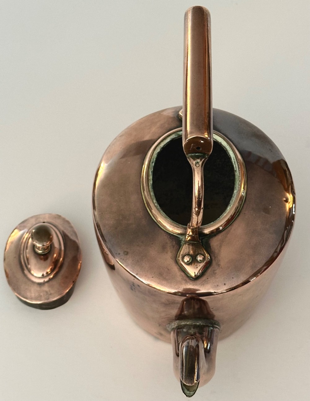 An antique copper tea kettle featuring a gooseneck spout, stationary overhead handle, and fitted lid with a central finial. View VII
