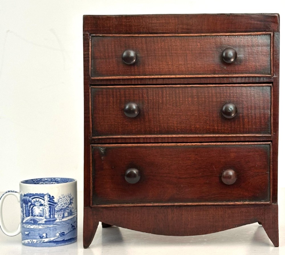 An antique mahogany miniature apprentice chest featuring three drawers with turned knobs and a shaped lower apron. View III