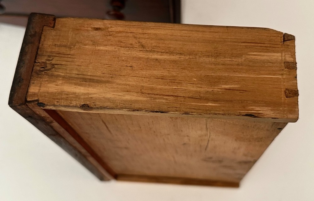 An antique mahogany miniature apprentice chest featuring three drawers with turned knobs and a shaped lower apron. View V