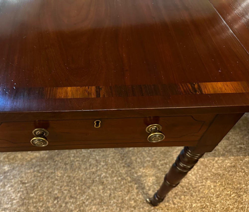 A Regency mahogany and rosewood sofa table featuring two frieze drawers, drop-leaf ends, turned legs, and brass castors. View IX
