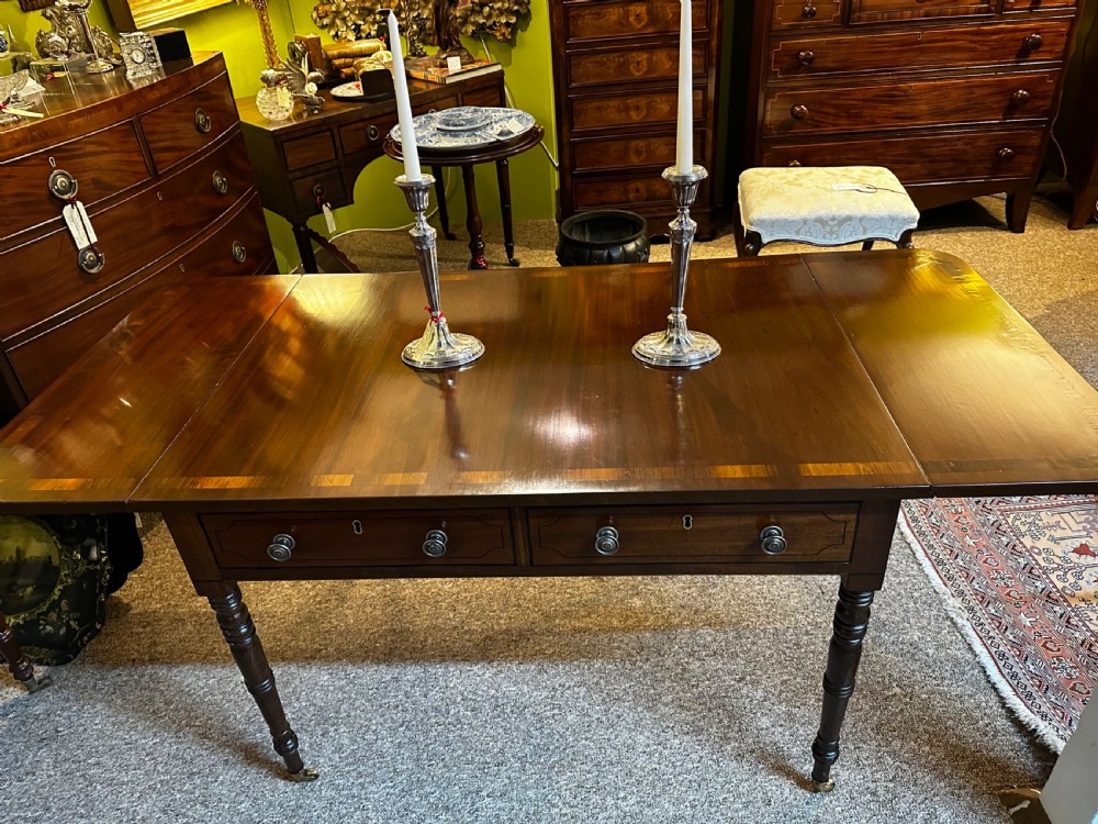 A Regency mahogany and rosewood sofa table featuring two frieze drawers, drop-leaf ends, turned legs, and brass castors. View XII
