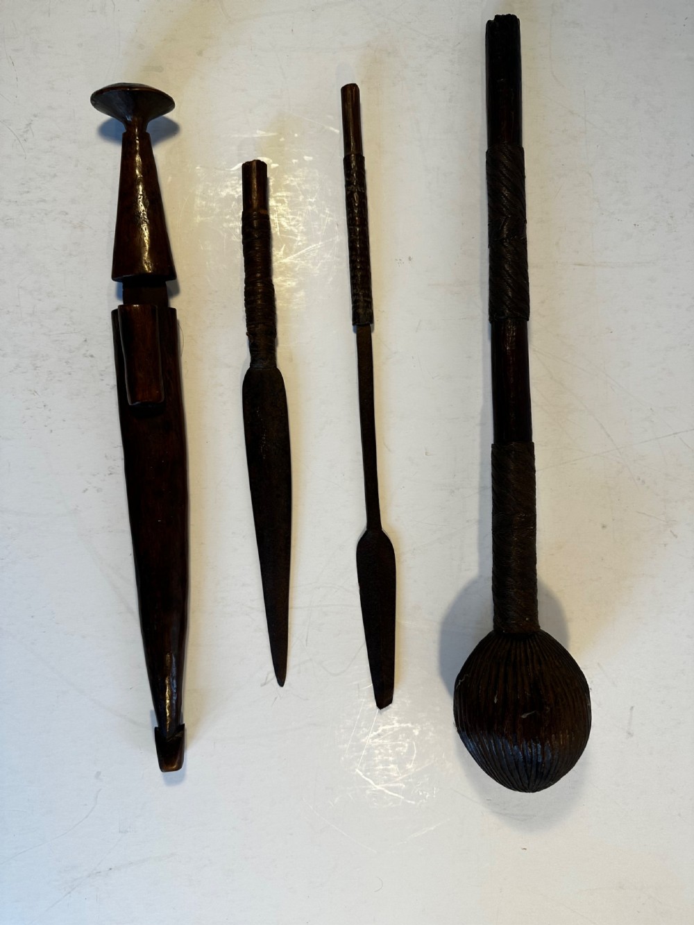 A collection of five traditional Zulu artefacts including a fluted knobkerrie club, a wooden dagger with sheath, and two wire-wrapped spearheads on a plain background. View XXI