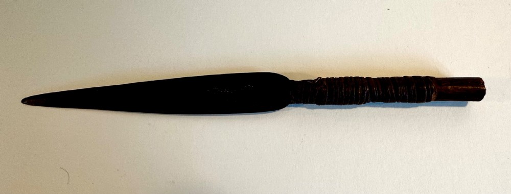 A collection of five traditional Zulu artefacts including a fluted knobkerrie club, a wooden dagger with sheath, and two wire-wrapped spearheads on a plain background. View IX