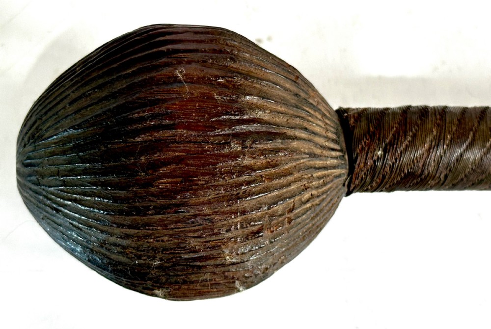 A collection of five traditional Zulu artefacts including a fluted knobkerrie club, a wooden dagger with sheath, and two wire-wrapped spearheads on a plain background. View X