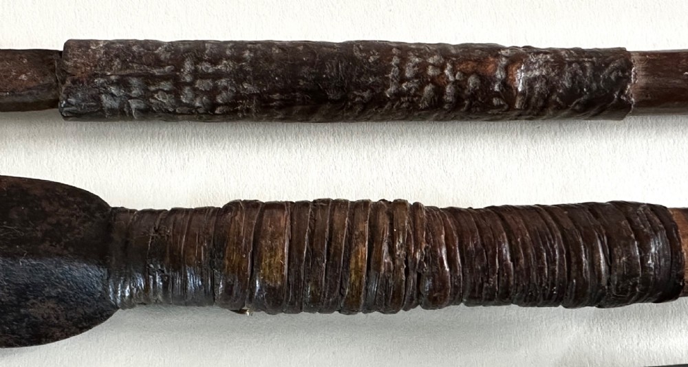A collection of five traditional Zulu artefacts including a fluted knobkerrie club, a wooden dagger with sheath, and two wire-wrapped spearheads on a plain background. View XVI