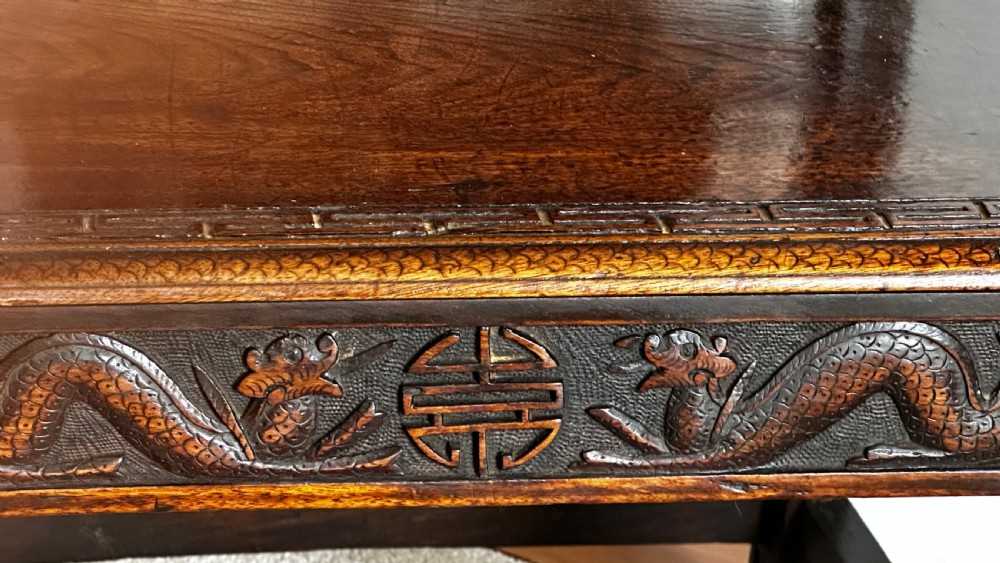 A dark brown carved wood armchair featuring openwork lattice panels, carved dragon motifs on the backrest, apron, and stretchers, and carved dragon heads forming the armrests. View VI