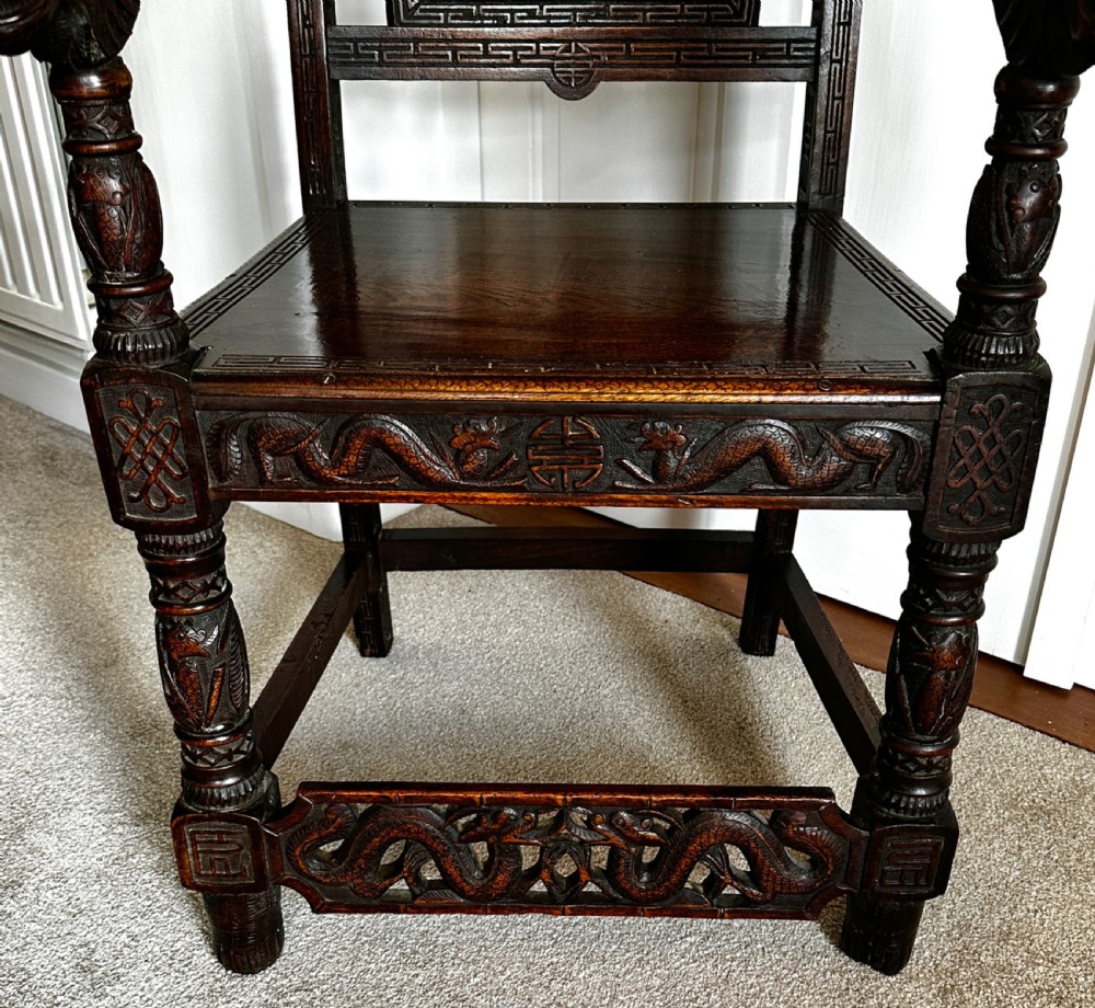 A dark brown carved wood armchair featuring openwork lattice panels, carved dragon motifs on the backrest, apron, and stretchers, and carved dragon heads forming the armrests. View VII