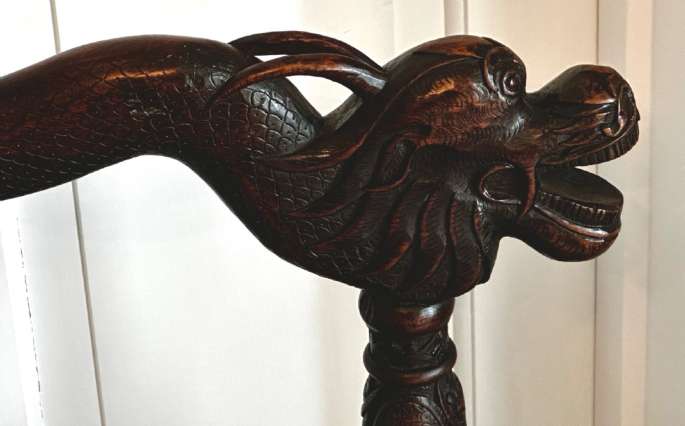 A dark brown carved wood armchair featuring openwork lattice panels, carved dragon motifs on the backrest, apron, and stretchers, and carved dragon heads forming the armrests. View VIII