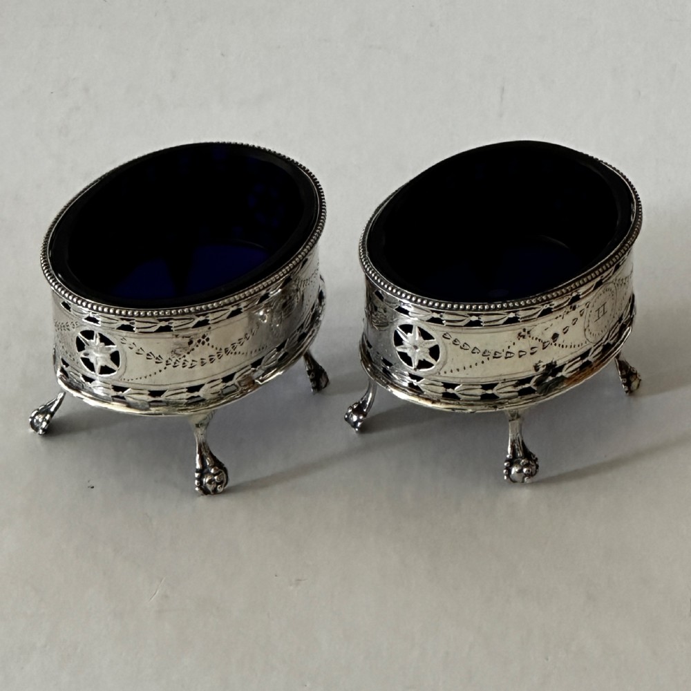 A pair of oval Georgian sterling silver open salt cellars with pierced swags, claw feet, and removable cobalt blue glass liners. View II