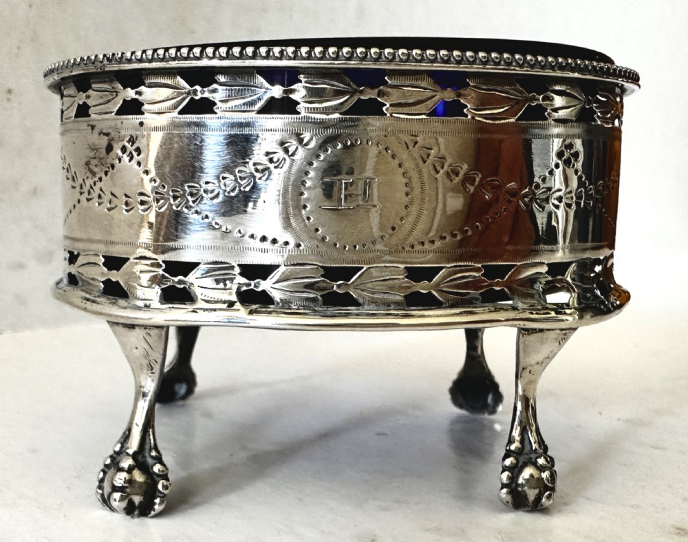 A pair of oval Georgian sterling silver open salt cellars with pierced swags, claw feet, and removable cobalt blue glass liners. View V