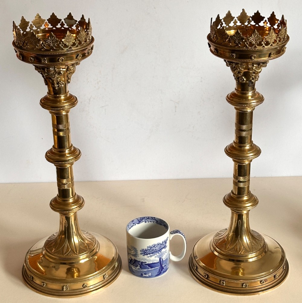 A pair of polished brass ecclesiastical candlesticks featuring pierced coronet galleries, knopped stems, and broad circular bases. View II