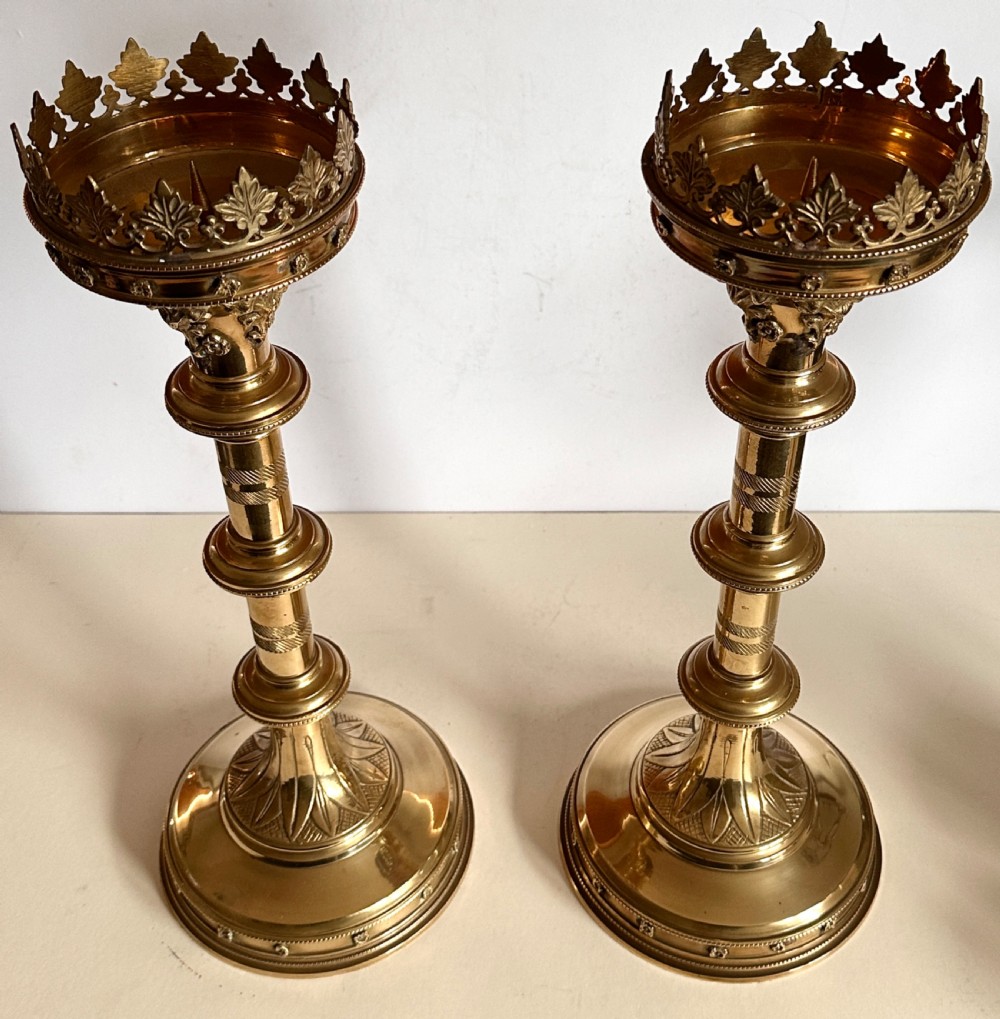 A pair of polished brass ecclesiastical candlesticks featuring pierced coronet galleries, knopped stems, and broad circular bases. View IV