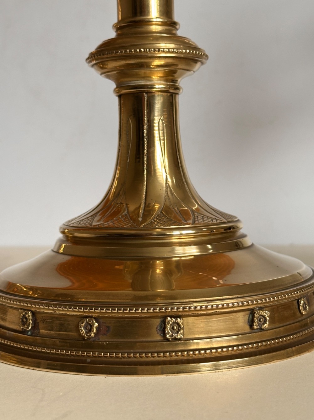 A pair of polished brass ecclesiastical candlesticks featuring pierced coronet galleries, knopped stems, and broad circular bases. View VI