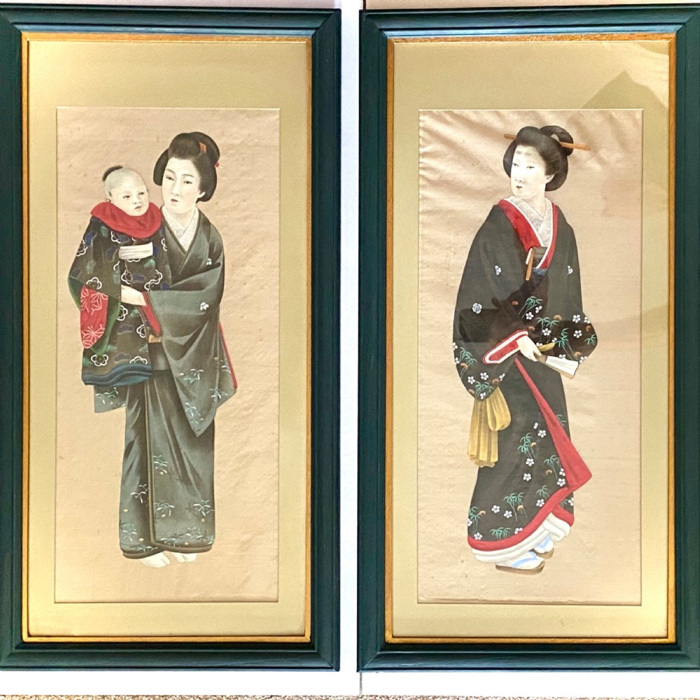 A pair of framed Japanese silk paintings depicting women wearing patterned kimono in dark green frames with gold bevelled mounts.
