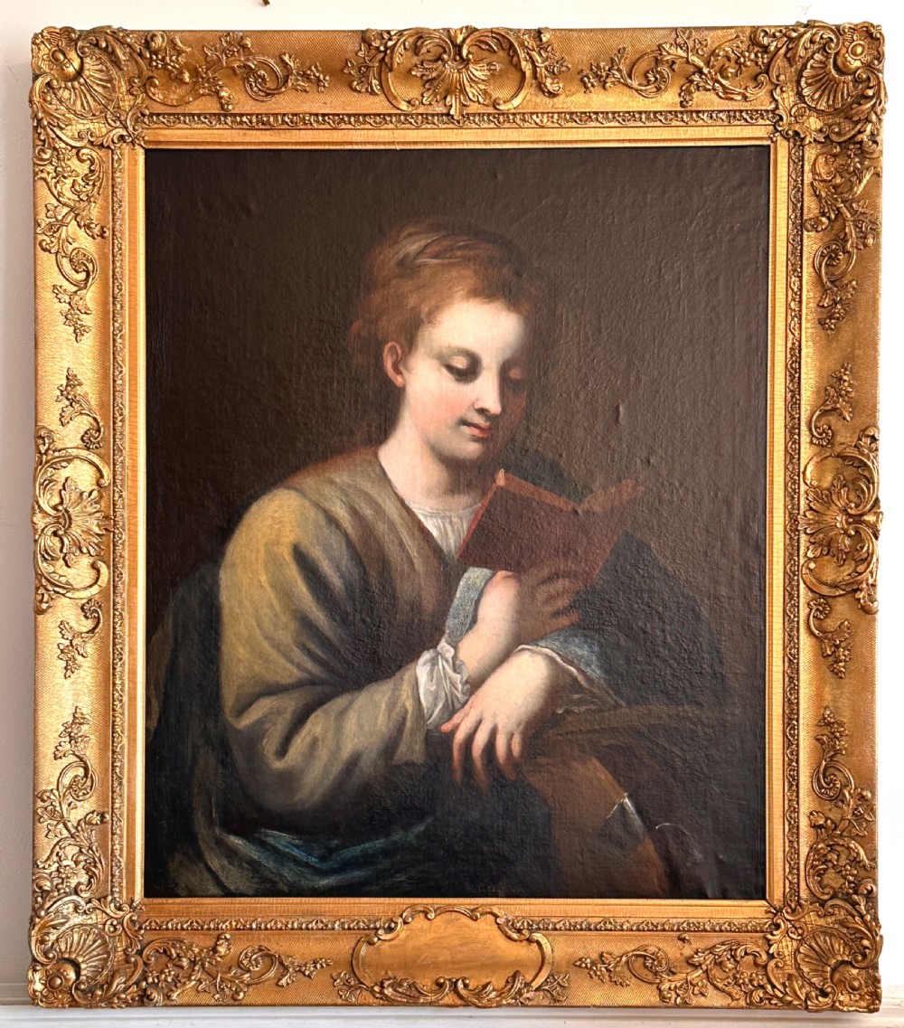 An 18th-century Italian oil painting on canvas depicting Saint Catherine reading a book, set within an ornate gilded carved frame.