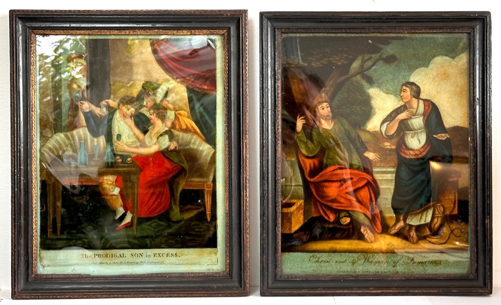 A pair of framed Georgian reverse glass paintings depicting biblical scenes inside dark ebonised wooden frames.