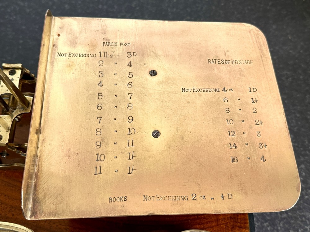 Victorian brass postal scales mounted on a dark mahogany wooden base with turned feet, including a set of nested brass weights. View III