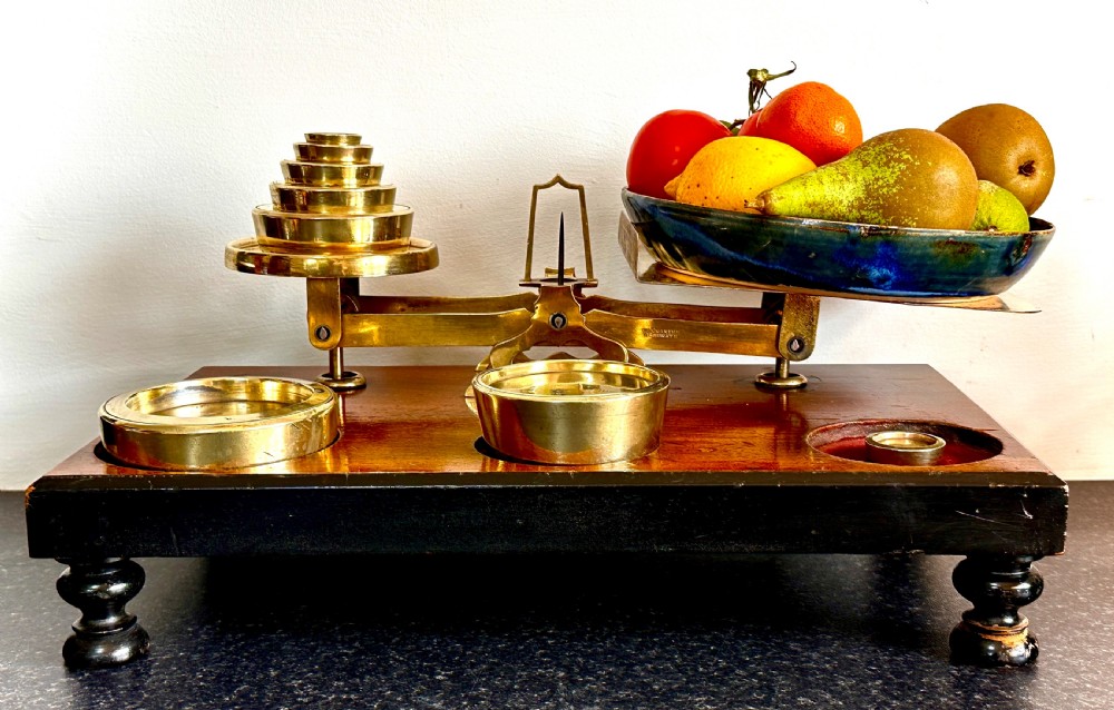 Victorian brass postal scales mounted on a dark mahogany wooden base with turned feet, including a set of nested brass weights. View IX