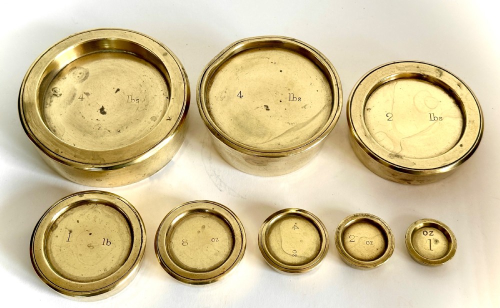 Victorian brass postal scales mounted on a dark mahogany wooden base with turned feet, including a set of nested brass weights. View XII