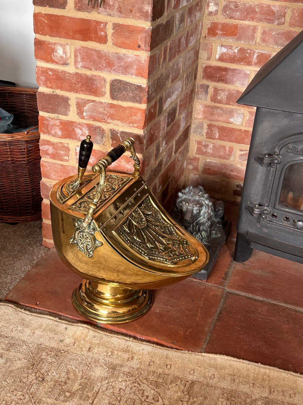 Victorian brass coal scuttle featuring elaborate repousse relief patterns, a pedestal base, and an ebonised wooden handle. View VIII