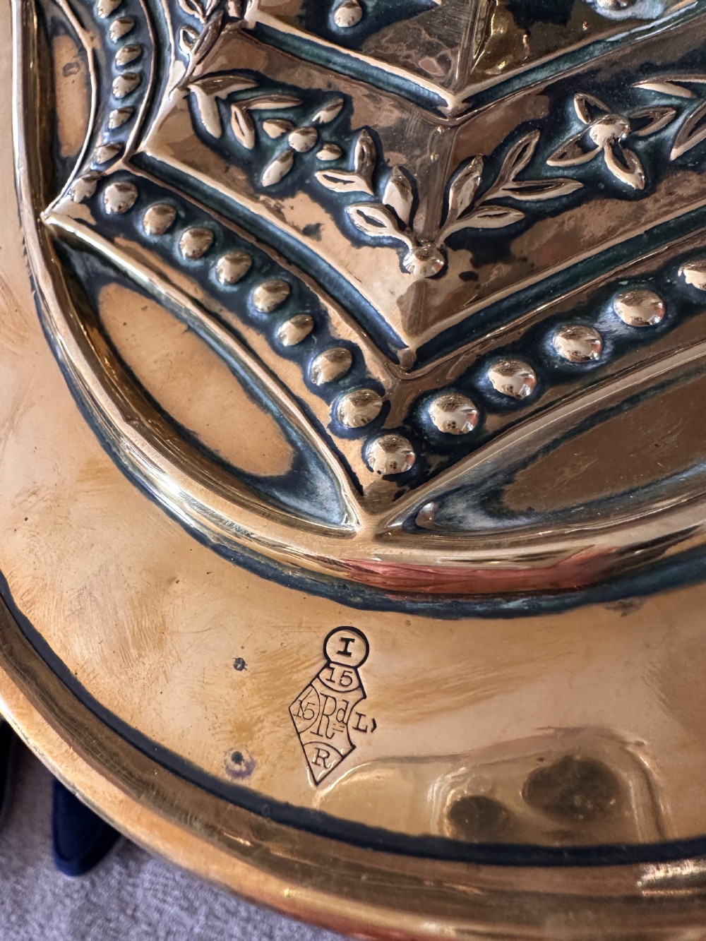Victorian brass coal scuttle featuring elaborate repousse relief patterns, a pedestal base, and an ebonised wooden handle. View X