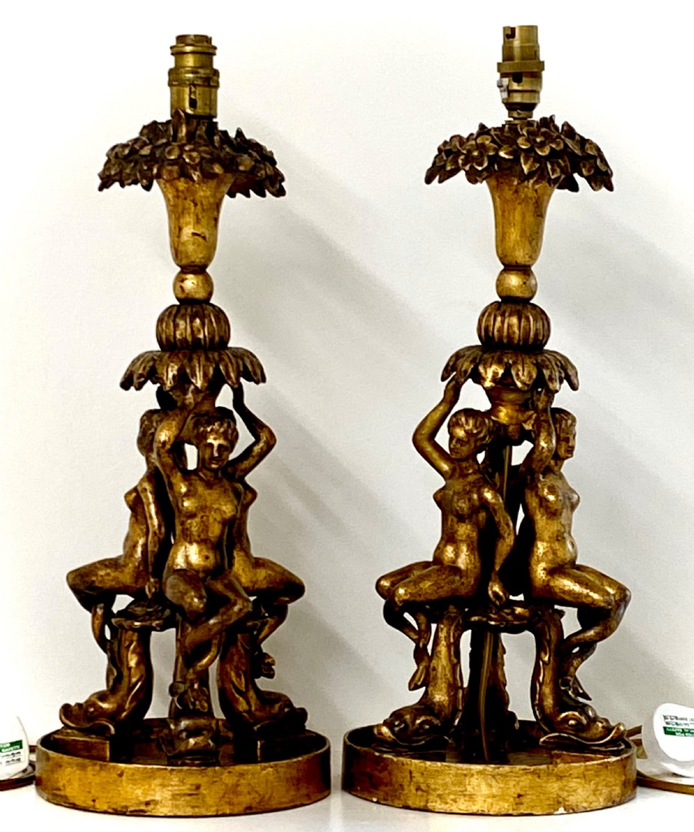 A pair of ornate Italian carved gilded table lamps featuring sculpted female figure supports and floral columns.