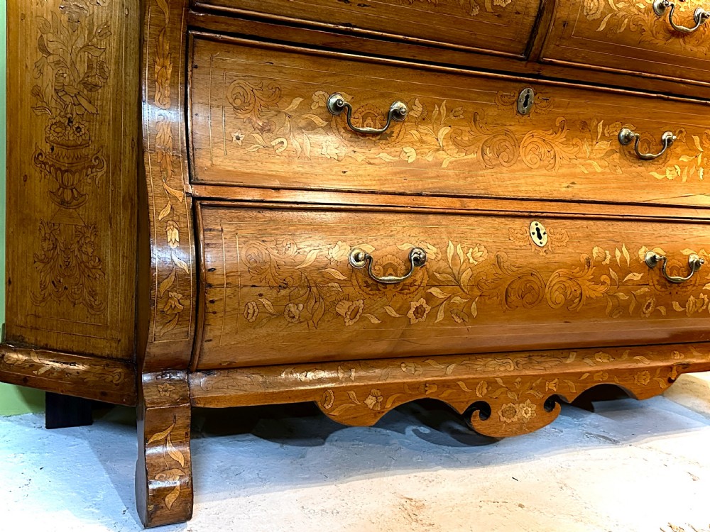 An 18th-century Dutch walnut display cabinet featuring a shaped bonnet top, glazed doors, intricate floral marquetry, and a lower bombe chest with drawers. View V