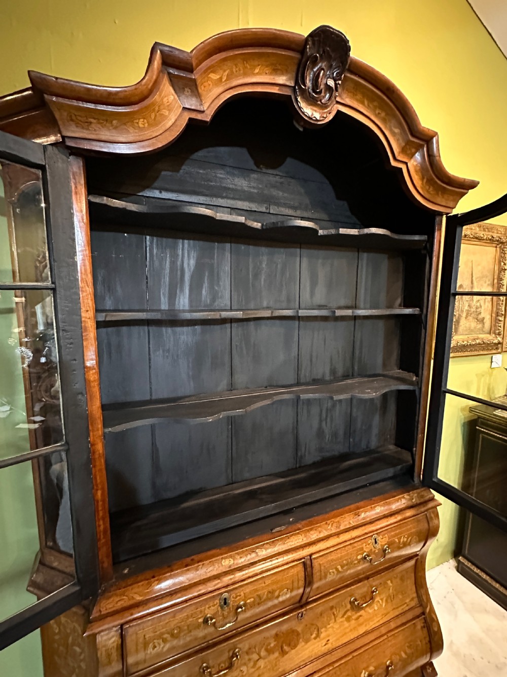 An 18th-century Dutch walnut display cabinet featuring a shaped bonnet top, glazed doors, intricate floral marquetry, and a lower bombe chest with drawers. View IX