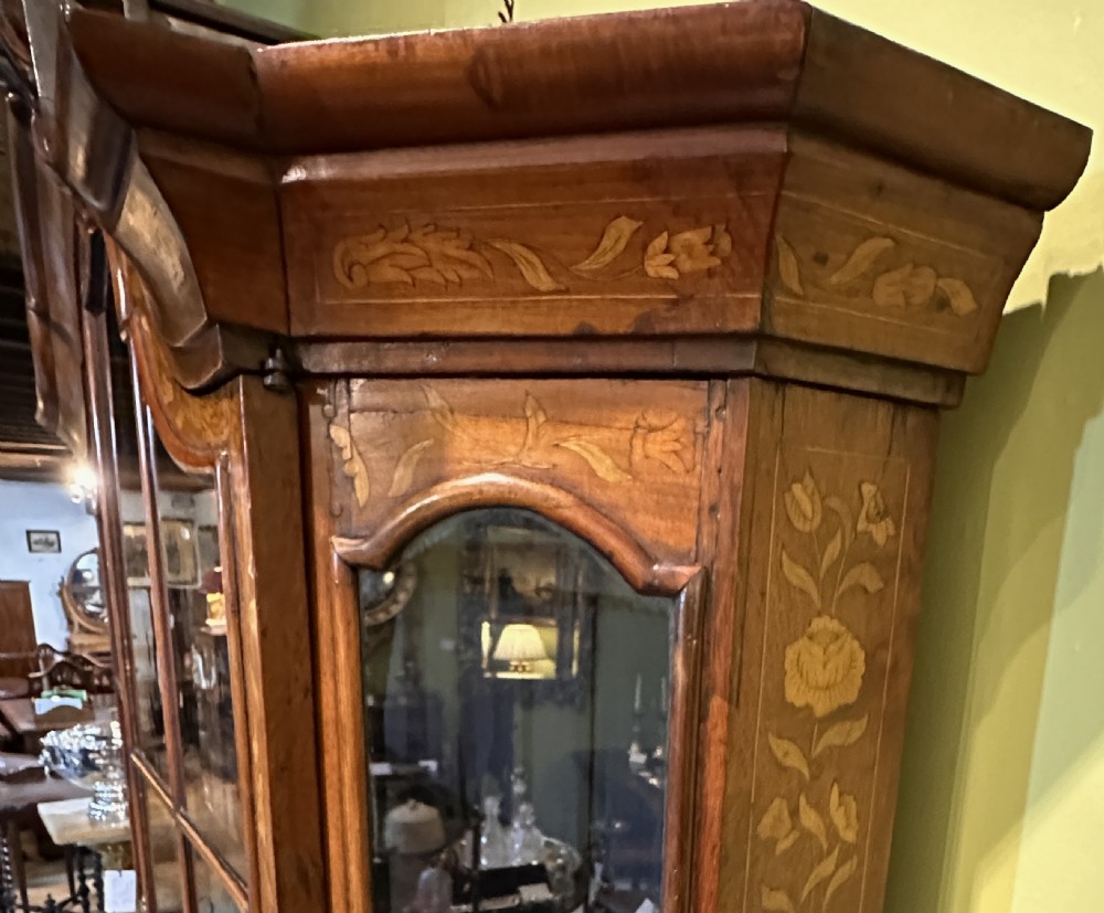 An 18th-century Dutch walnut display cabinet featuring a shaped bonnet top, glazed doors, intricate floral marquetry, and a lower bombe chest with drawers. View XI