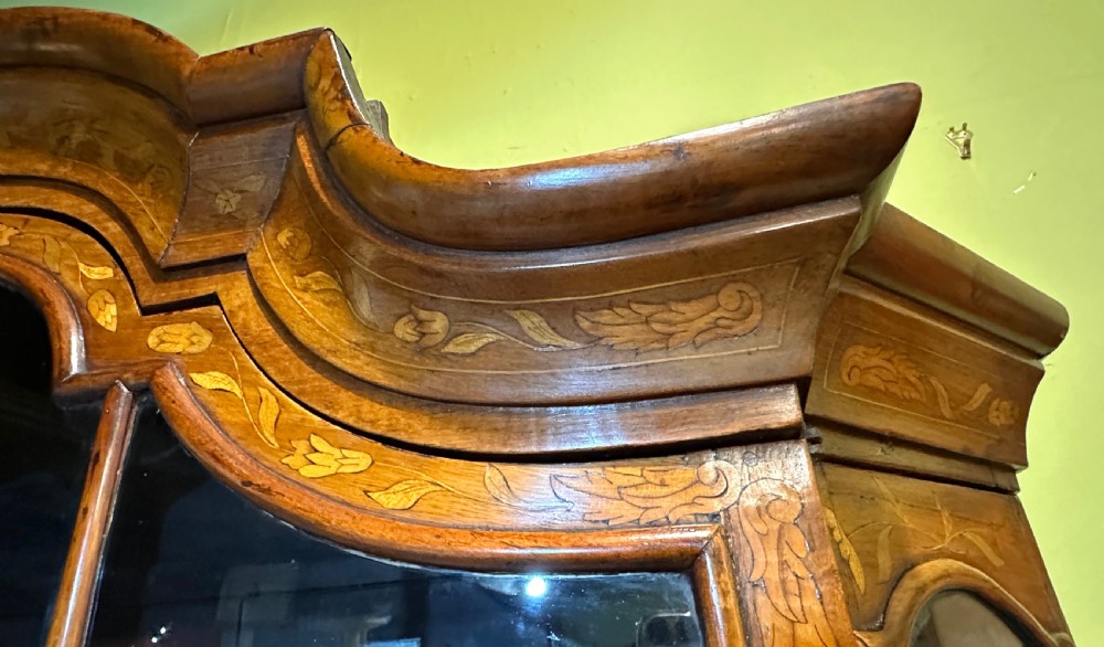 An 18th-century Dutch walnut display cabinet featuring a shaped bonnet top, glazed doors, intricate floral marquetry, and a lower bombe chest with drawers. View XIII