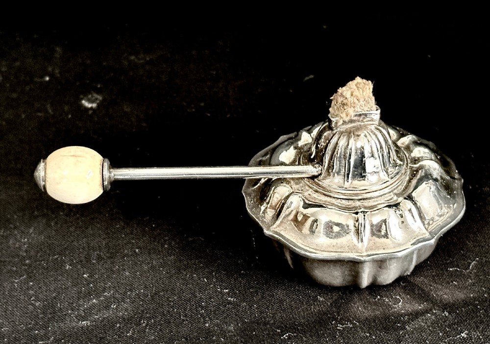 A silver-plated tea kettle with an overhead handle and spirit burner resting on a matching carved four-legged stand. View IX