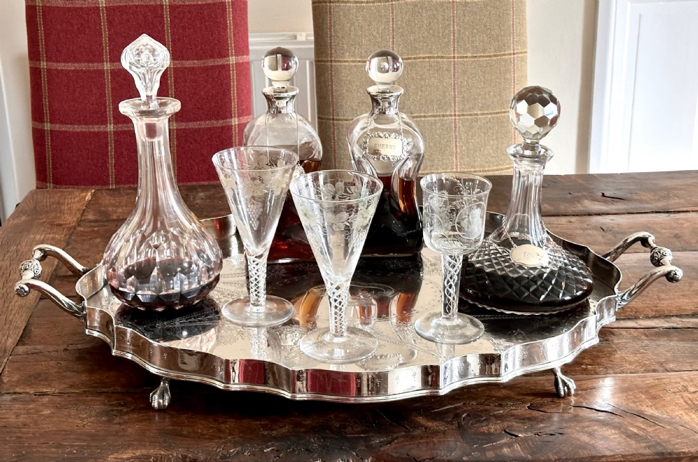A large oval silver-plated tray featuring a scalloped gallery border, twin side handles, etched foliate surface decoration, and cast feet. View VI